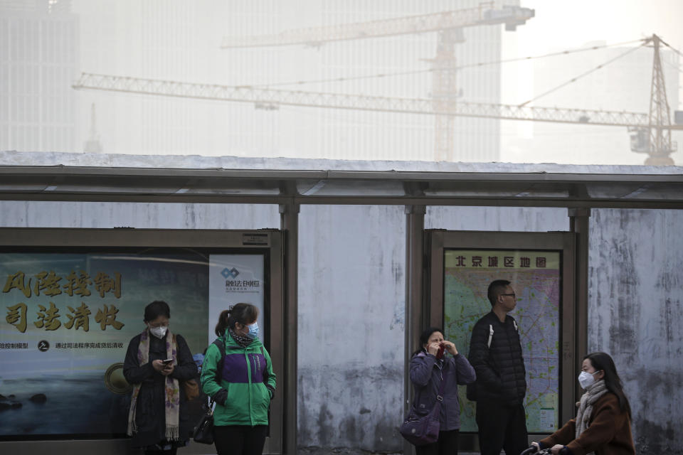 Commuters with masks for protection against the pollution wait for buses at the Central Business District in Beijing, Tuesday, Nov. 13, 2018. Chinese Premier Li Keqiang says the country needs reforms to support business to help drive growth as it weathers a trade war with the U.S., rather than more economic stimulus. Li said Tuesday in Singapore that China can energize its slowing economy by adjusting policies, such as streamlining bureaucratic procedures like business registrations, taxes and fees. (AP Photo/Andy Wong)