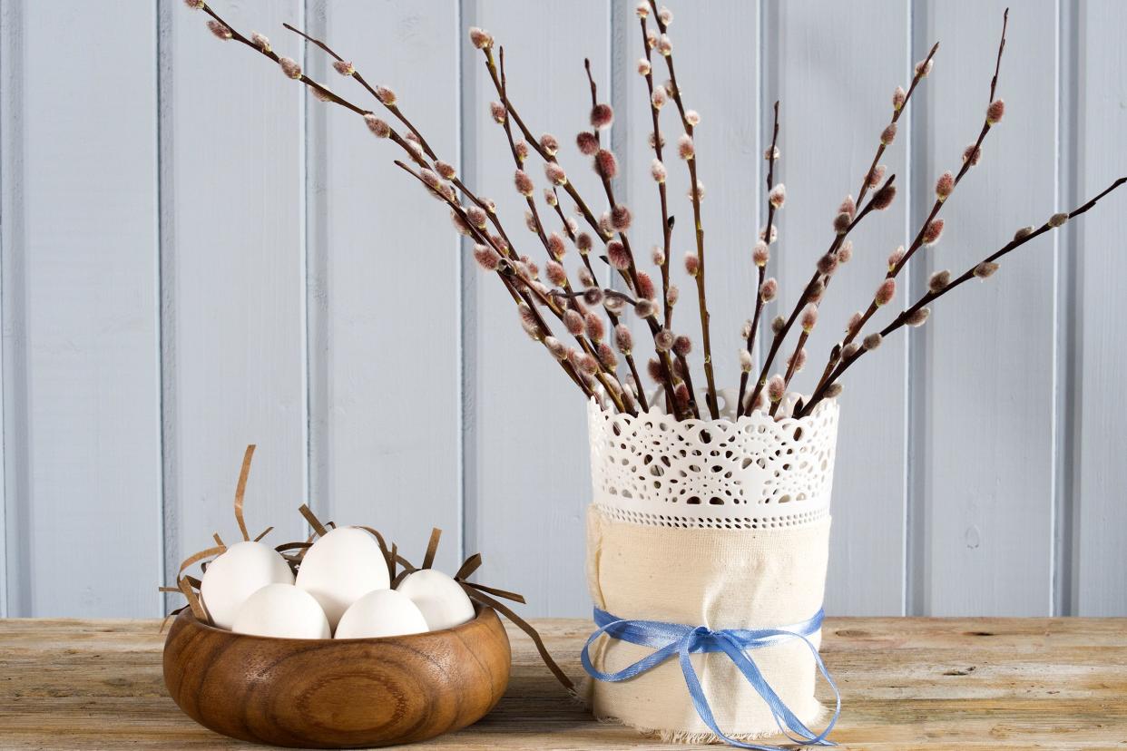 Branches in a vase next to Easter eggs