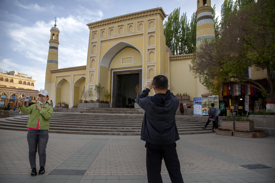 Visitantes se toman fotos frente a la Mezquita Id Kah de Kashgar, en la Región Autónoma Uigur de Xianjiang, al oeste de China, el 19 de abril del 2021, durante una visita de periodistas extranjeros organizada por las autoridades. (AP Photo/Mark Schiefelbein)