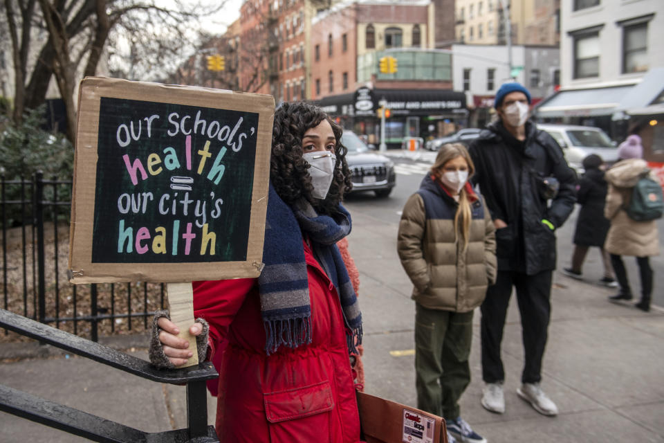Ms. Kaiser, a teacher from the Earth school, holds a sign in solidarity with other teachers who are speaking out on issues related to lack of COVID testing for students on Tuesday, Dec. 21, 2021, in New York. (AP Photo/Brittainy Newman)