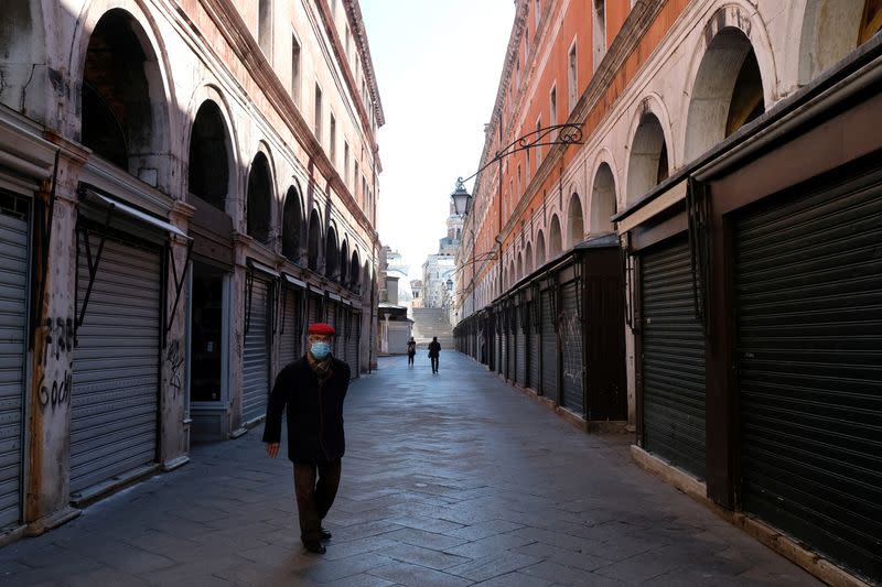 A man wearing a protective mask in an empty street of Venice on Sunday with an unprecedented lockdown across of all Italy imposed to slow the outbreak of coronavirus, in Venice