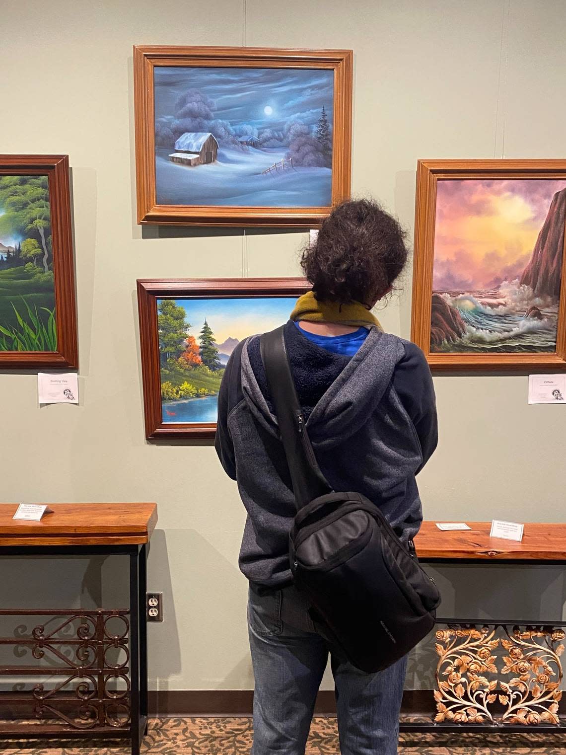 Wolf Gordon-Escobar views a sample of Bob Ross’ paintings at NC Wesleyan University.