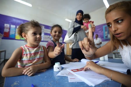 An electoral worker gestures after allowing a child to get her finger inked at a polling station during presidential election in Tunis