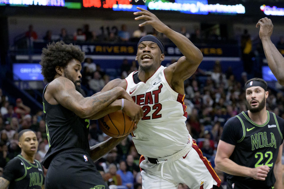 New Orleans Pelicans forward Naji Marshall, front left, and Miami Heat forward Jimmy Butler (22) get tangled up under the basket during the second half of an NBA basketball game in New Orleans, Friday, Feb. 23, 2024. (AP Photo/Matthew Hinton)