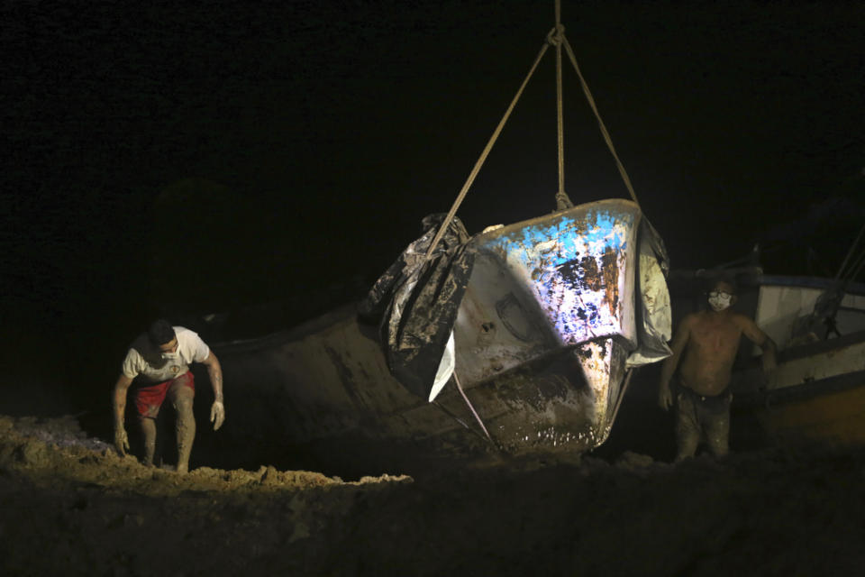 A boat that was carrying decomposing corpses is lifted to shore by authorities at the Vila do Castelo port in Braganca, Brazil, early Monday, April 15, 2024. Security forces and forensics were dispatched to the area after fishermen reported on Saturday spotting the boat off the coast of Para state. (AP Photo/Raimundo Pacco)