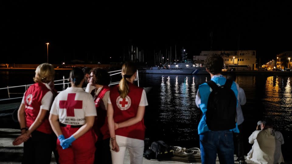 Members of the Red Cross wait outside a hangar in Kalamata, Greece, where migrants have been temporarily housed, following the sinking of a fishing boat carrying hundreds of passengers. - Byron Smith/Getty Images
