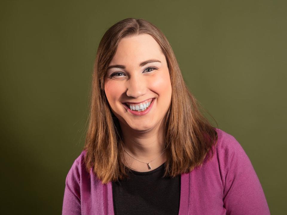 Sarah McBride smiles for a portrait against a green background