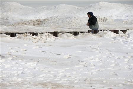 A man walks along a snow covered beach in Chicago, Illinois, January 8, 2014. REUTERS/Jim Young