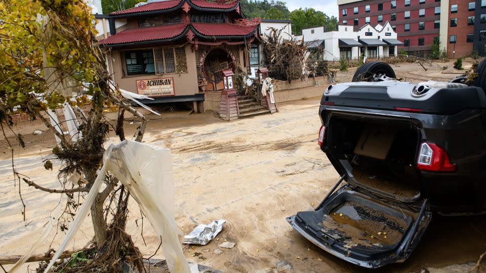 Ein durch Überschwemmungen beschädigtes Auto liegt nach Helenes Unfall am 1. Oktober 2024 in Asheville kopfüber vor dem Ichiban Restaurant im Biltmore Village. -Mélissa Sue Gerrits/Getty Images