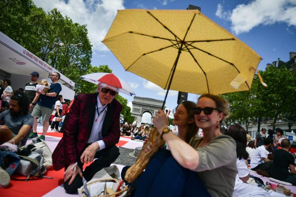 Revelers enjoy the picnic under an umbrella.