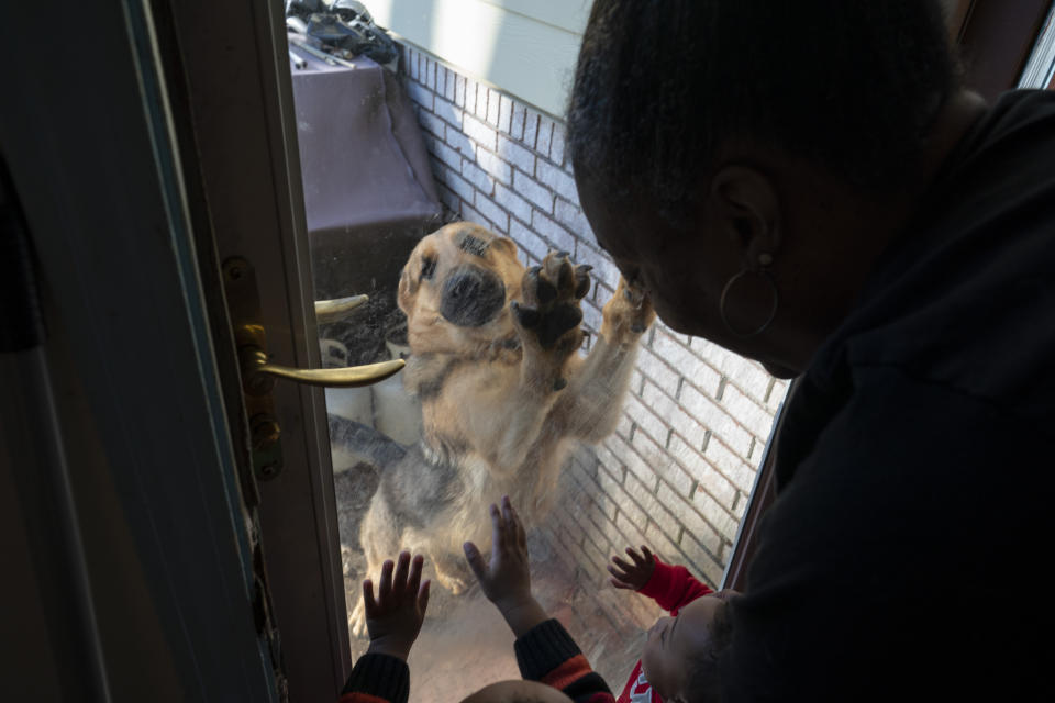 Shelonda Lyons looks after her grandchildren, Malik Lyons-Law and Adrien Lyons, as they play with their dog on Saturday, Feb. 5, 2022, in Birmingham, Ala. (AP Photo/Wong Maye-E)