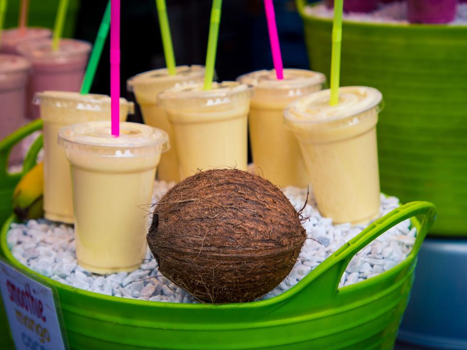 coconut smoothies on rocks in a green basket next to a coconut