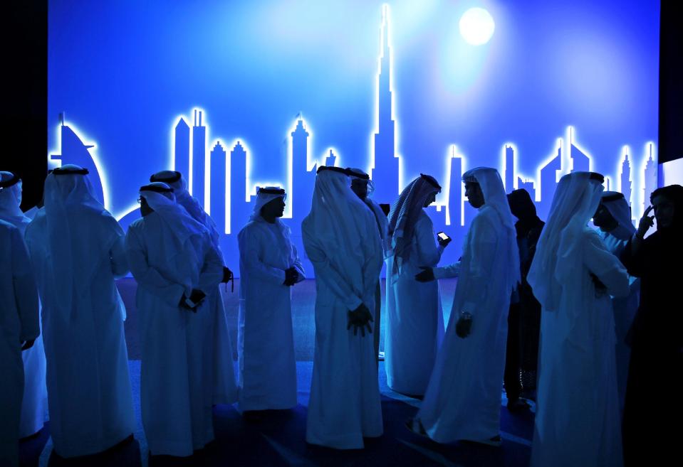 Emirati attendees wait in front of an image of the city's skyline in Dubai, United Arab Emirates, Wednesday, March 5, 2014. After years of chasing the biggest and the best, the fast-growing Mideast city of Dubai is turning to technology to help the little things in life run more smoothly. (AP Photo/Kamran Jebreili)