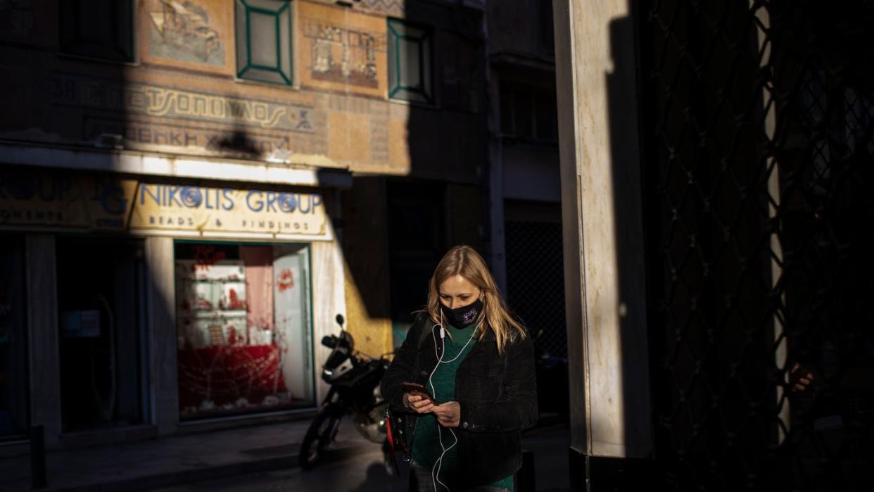 Eine Frau, die eine schützende Gesichtsmaske trägt, geht im Zentrum von Athen.