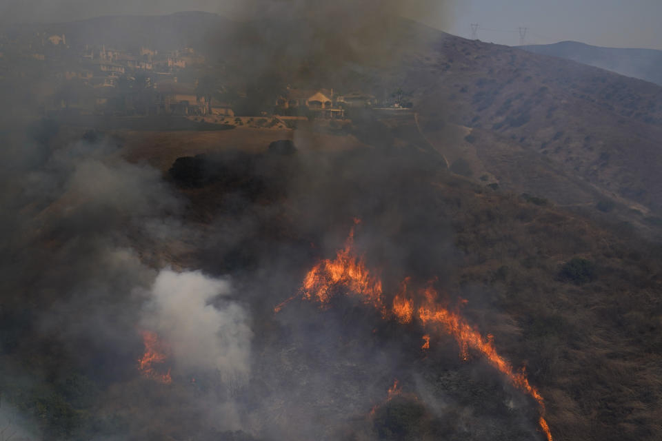 The Blue Ridge Fire burns near homes Tuesday, Oct. 27, 2020, in Yorba Linda, Calif. Crews tried to beat back two out-of-control wildfires in Southern California on Tuesday that have kept tens of thousands of people out of their homes even as another round of dangerous fire weather raises the risk for flames erupting across the state. (AP Photo/Jae C. Hong)