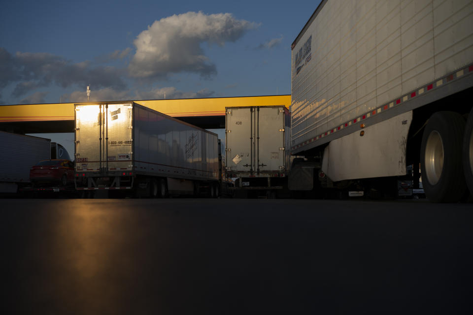 In this April 6, 2020, photo, tractor-trailers line up to fuel in the setting sun at the Love's Travel Stop truck stop in Greenville, Va. During the coronavirus outbreak, truckers continue to work to keep store shelves full. (AP Photo/Carolyn Kaster)