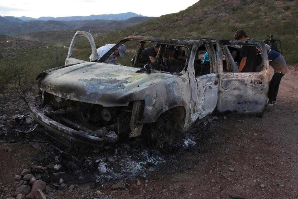 Members of the Lebaron family examine the burned car where some of the nine murdered members of the family were killed and burned in the Sonora mountains. (Photo: STR via Getty Images)