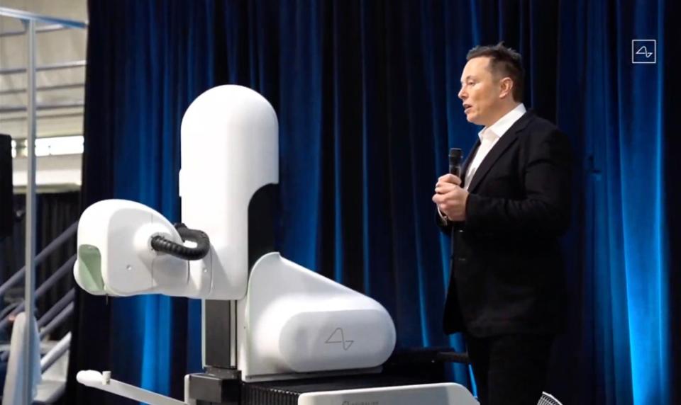 Musk is seen standing next to the surgical robot that connects the chip to the brain. Neuralink/AFP via Getty Images