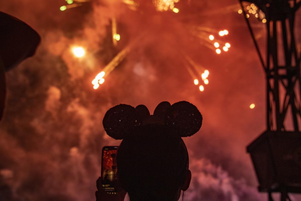 Fireworks explode over guest watching Flower and Garden Festival at Epcot at Walt Disney World.