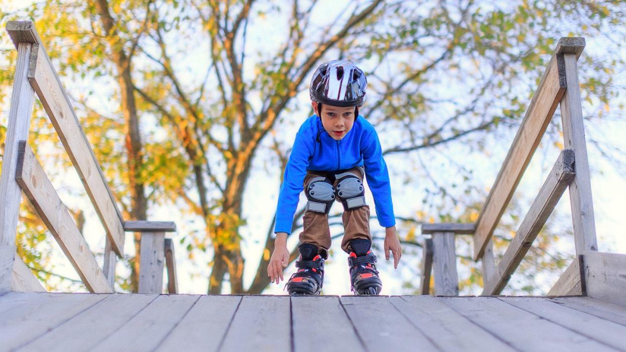 boy roller blading with helmet and knee pads