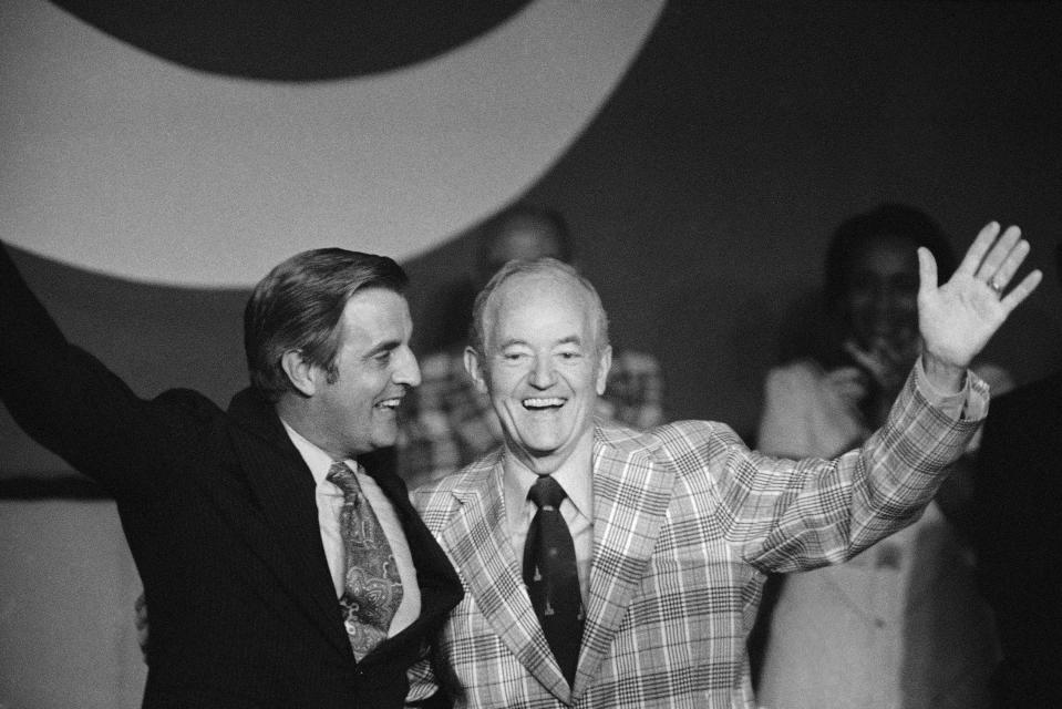 FILE - U.S. Vice President Walter Mondale, left and Sen. Hubert Humphrey share a laugh after they embraced upon greeting each other on the podium of the National Education Assn. meeting, July 5, 1977 in Minneapolis, Minn, where Mondale was guest speaker and Humphrey was presented the "Friend of Education Award." Former President Donald Trump’s planned campaign visit to Minnesota will mark his return to a traditionally Democratic state he has long argued he could carry. Trump will take a break from his hush money trial in New York to speak at a Minnesota GOP fundraiser Friday. (AP Photo/Jim Mone, File)