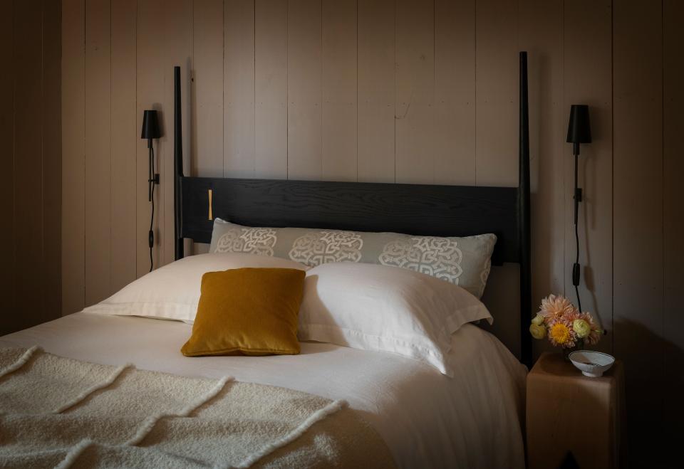 One of the three bedrooms in the barn features an ebonized oak bed by Chris Earl with Coyuchi bedding in organic linen. The brass-and-bronze “Matchstick” sconces are from Urban Electric Co.