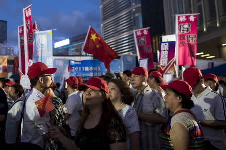 Pro-China supporters hold Chinese national flags at a demonstration supporting a Beijing-backed electoral reform outside the Legislative Council building in Hong Kong, China June 17, 2015. REUTERS/Tyrone Siu