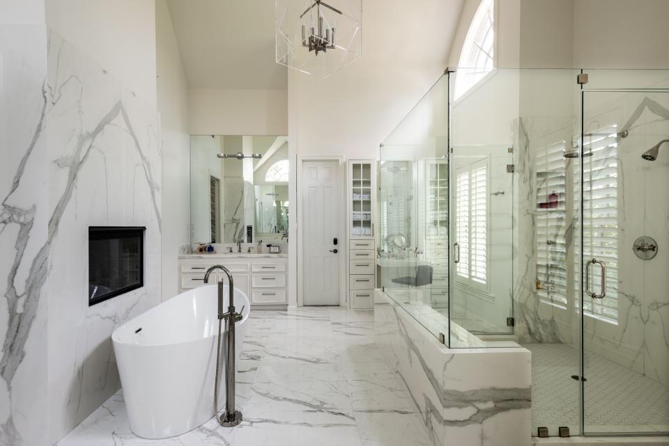 The pitched ceiling washes the bathroom in gorgeous southern light, which bounces off the white Neolith sintered stone seen on nearly every surface. A pass-through fireplace adds a spa-like touch. All the fixtures are polished nickel; the acrylic light fixture was custom-designed by Loya.