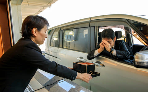 A man bows as he reserves ashes of a family member - Credit: Androniki Christodoulou for the Telegraph 