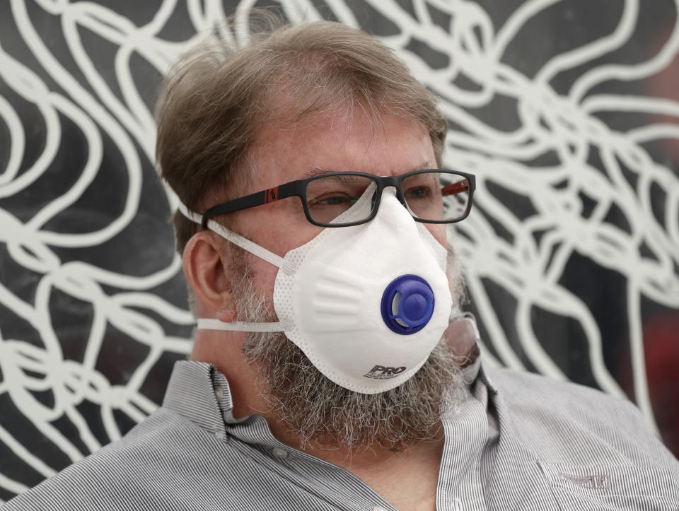 A commuter wears a mask as smoke shrouds the Australian capital of Canberra, Australia, Thursday, Jan. 2, 2020. Australia deployed military ships and aircraft to help communities ravaged by apocalyptic wildfires that destroyed homes and sent thousands of residents and holidaymakers fleeing to the shoreline. (AP Photo/Mark Baker)