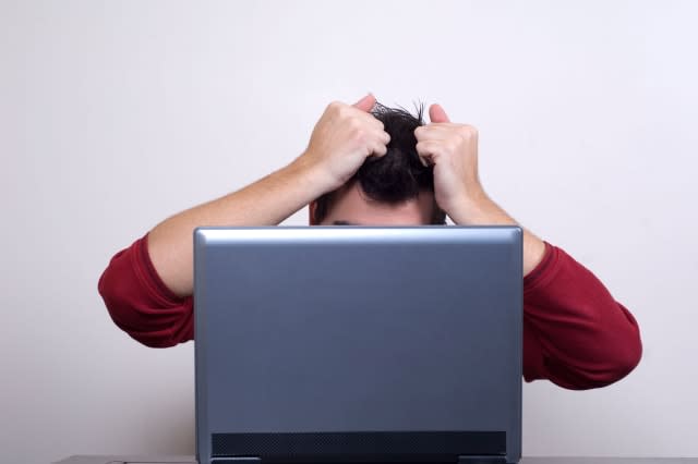 AN10EJ Man pulling his hair behind laptop computer