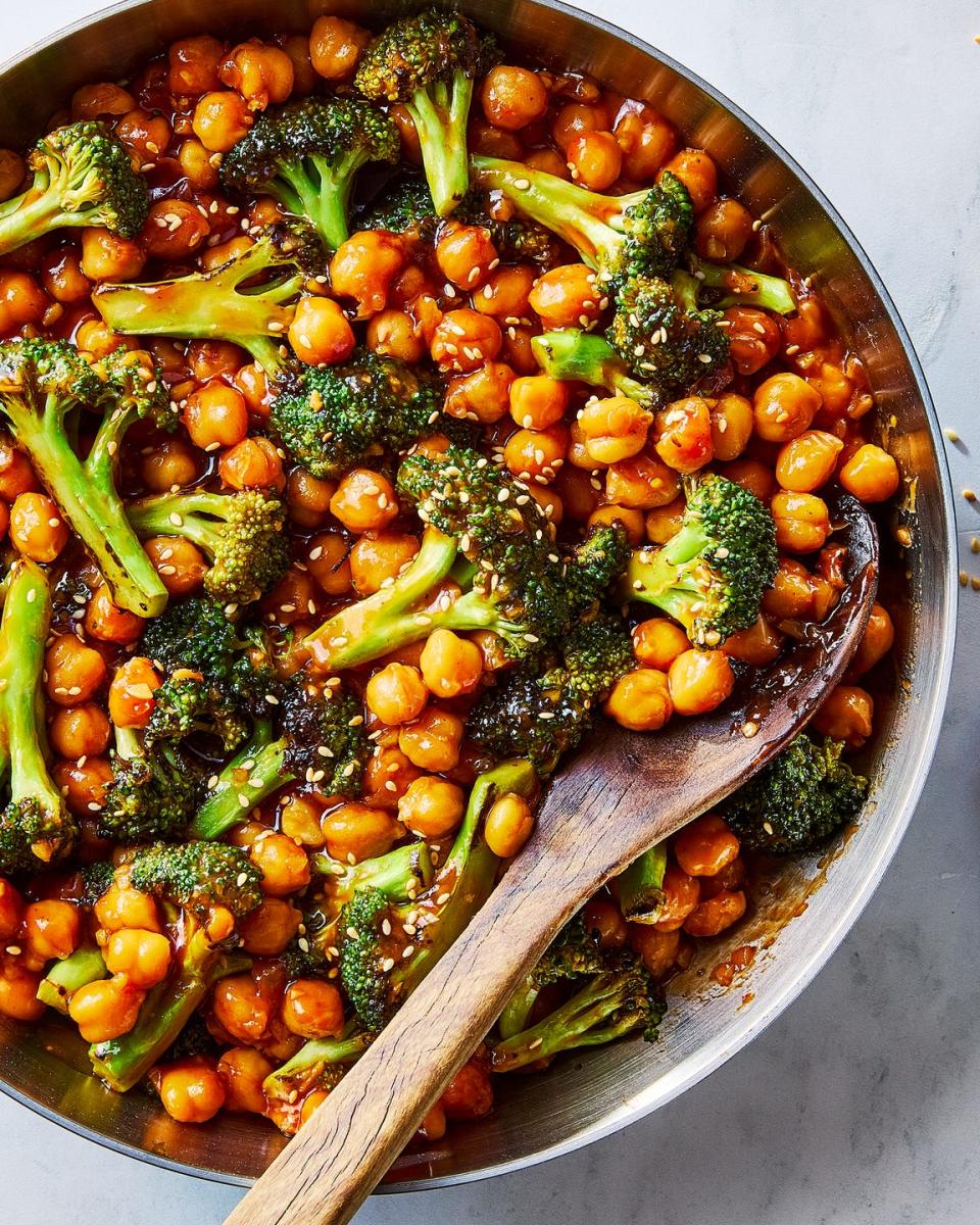 sticky sesame chickpeas and broccoli in a pan with a wooden spoon