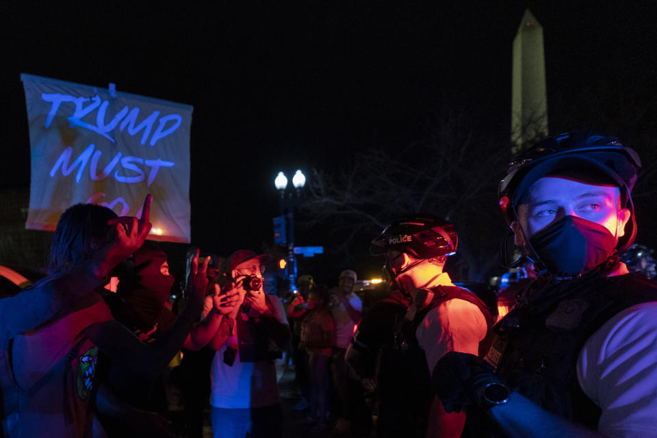 A members of the United States Secret Service Uniformed Division police stand around a police car in front of protesters near the White House with the Washington Monument seen in the distance during the fourth night of the Republican National Convention in Washington, Thursday, Aug. 27, 2020. (AP Photo/Carolyn Kaster)