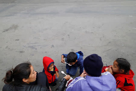 Members of a migrants caravan from Central America eat along a street as they finish their caravan journey through Mexico, prior to preparations for an asylum request in the U.S., in Tijuana, Baja California state, Mexico April 26, 2018. REUTERS/Edgard Garrido