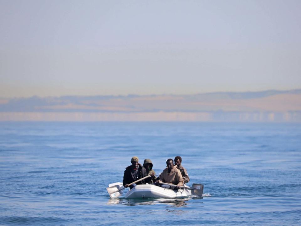Four men off the coast of France, some using shovels as paddles, use a small dinghy to cross the English Channel on 7 August 2020: Getty