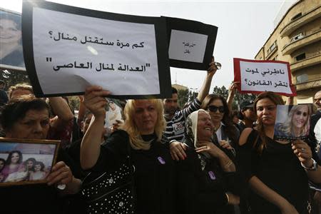 Families of Rola Yacoub and Manal Assi, victims of domestic violence, react as they carry their pictures and banners during a march against domestic violence against women, marking International Women's Day in Beirut March 8, 2014. REUTERS/Jamal Saidi