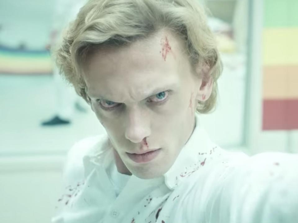 vecna, before he became vecna, fighting eleven as an orderly in stranger things, standing in a rainbow decorated room with patches of blood on his face and an intense expression