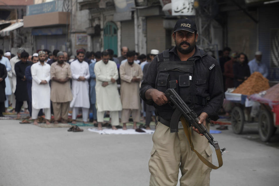 In this Friday, Nov. 2, 2018, photo a Pakistani police officer stands alert as people offer Friday prayers in Peshawar, Pakistan. (AP Photo/Muhammad Sajjad)
