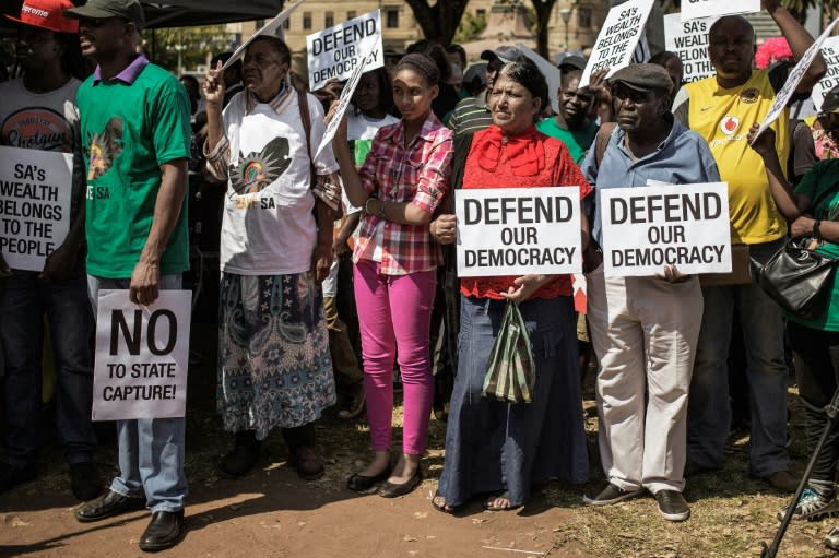 People hold placards during a rally outside the South African National Treasury to protest against President Jacob Zuma in Pretoria on April 3, 2017