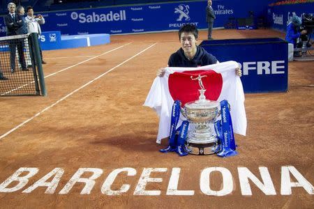 Kei Nishikori of Japan holds up the Japanese flag as he poses with the trophy after beating Pablo Andujar of Spain to win the Barcelona Open tennis tournament in Barcelona April 26, 2015. REUTERS/Gustau Nacarino