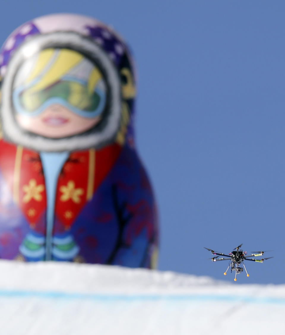 In this Friday Feb. 7 photo, a drone camera flies about the slopestyle course during a freestyle skiing slopestyle training session at the Rosa Khutor Extreme Park ahead of the 2014 Winter Olympics, Friday, Feb. 7, 2014, in Krasnaya Polyana, Russia. (AP Photo/Sergei Grits)