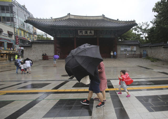 A family braves the strong wind and rain caused by Typhoon Lingling in Seoul, South Korea, Saturday, Sept. 7, 2019. A typhoon passed along South Korea's coast Saturday, toppling trees, grounding planes and causing at least two deaths before the storm system made landfall in North Korea. (AP Photo/Ahn Young-joon)