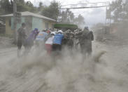 Police and military help push a vehicle along a road covered in volcanic ash at a village beside Taal volcano where residents have evacuated to safer ground in Agoncillo, Batangas province, southern Philippines on Saturday Jan. 18, 2020. The Taal volcano near the Philippine capital emitted more ash clouds Saturday, posing the threat of another eruption. (AP Photo/Aaron Favila)