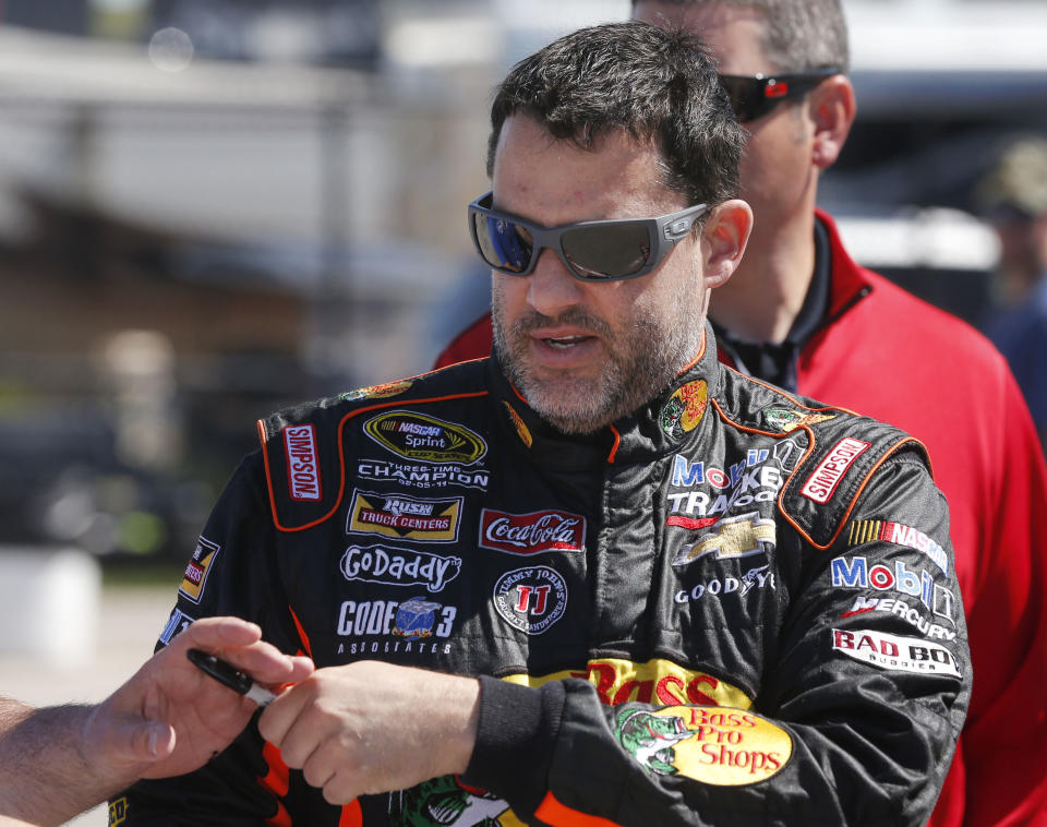 Driver Tony Stewart signs autographs while walking through the garage area, Friday, May 9, 2014, at Kansas Speedway in Kansas City, Kan., for Saturday night's NASCAR Sprint Cup series auto race. (AP Photo/Orlin Wagner)