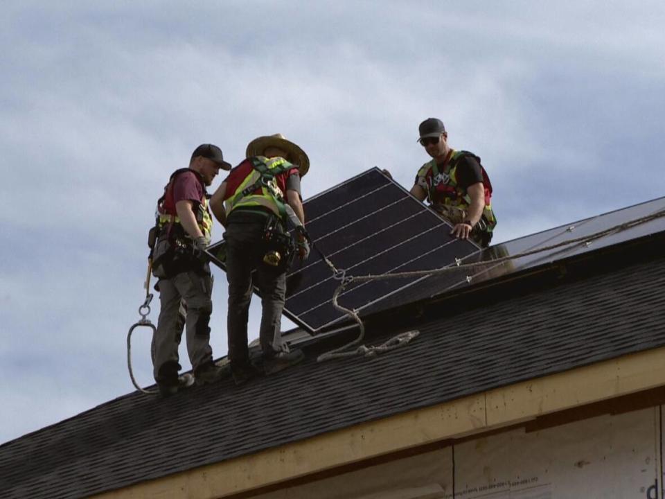 Workers install solar panels on a Calgary home, a project that could now be financed by the new city program. (Justin Pennell/CBC - image credit)