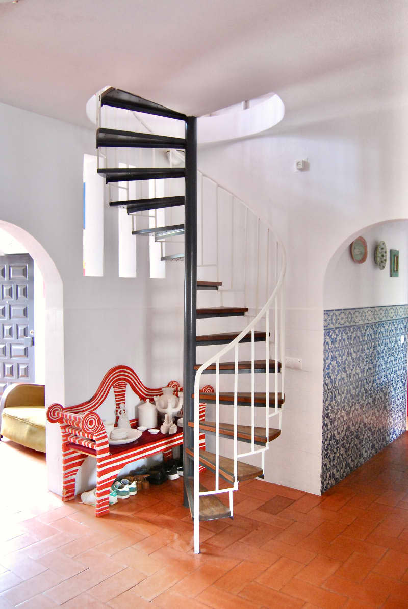 Red and white striped bench under spiral staircase.