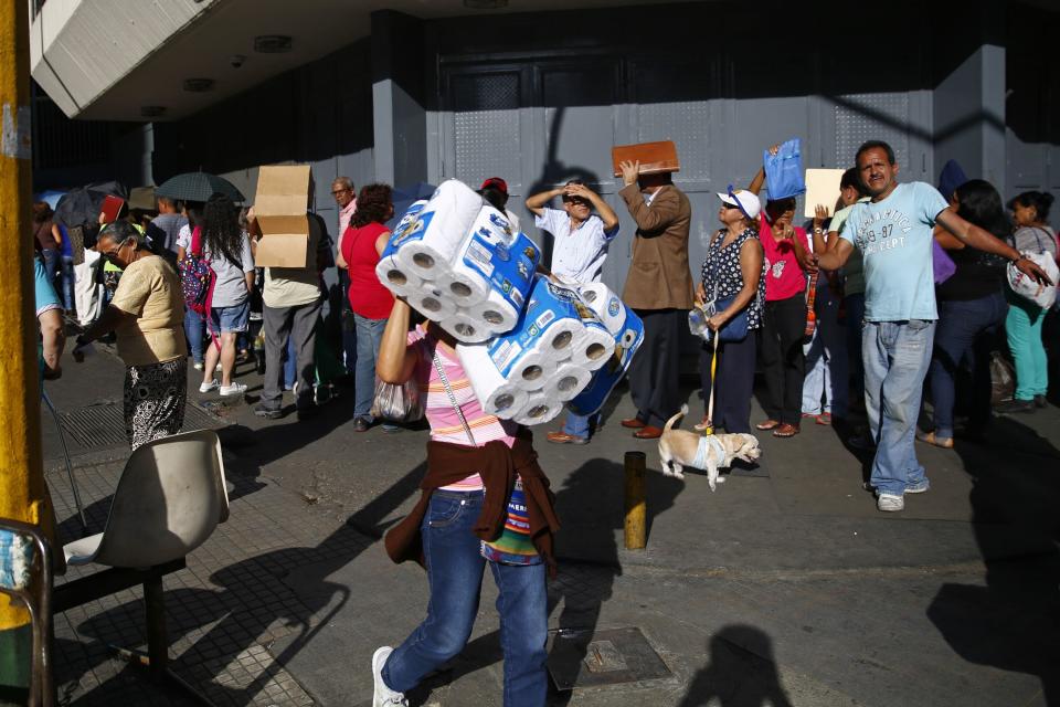 People line up outside a supermarket to buy toilet paper in Caracas January 12, 2015. Lines swelled at Venezuelan supermarkets on Friday with shoppers queuing up by the hundreds to seek products ranging from chicken to laundry detergent, as a holiday slowdown in deliveries sharpened the OPEC nation's nagging product shortages. Queues snaked around the block at grocery stores and pharmacies around the country, with consumers in some cases gathering before dawn under the gaze of national guard troops posted to maintain order. Reuters/Jorge Silva (VENEZUELA - Tags: POLITICS BUSINESS SOCIETY)