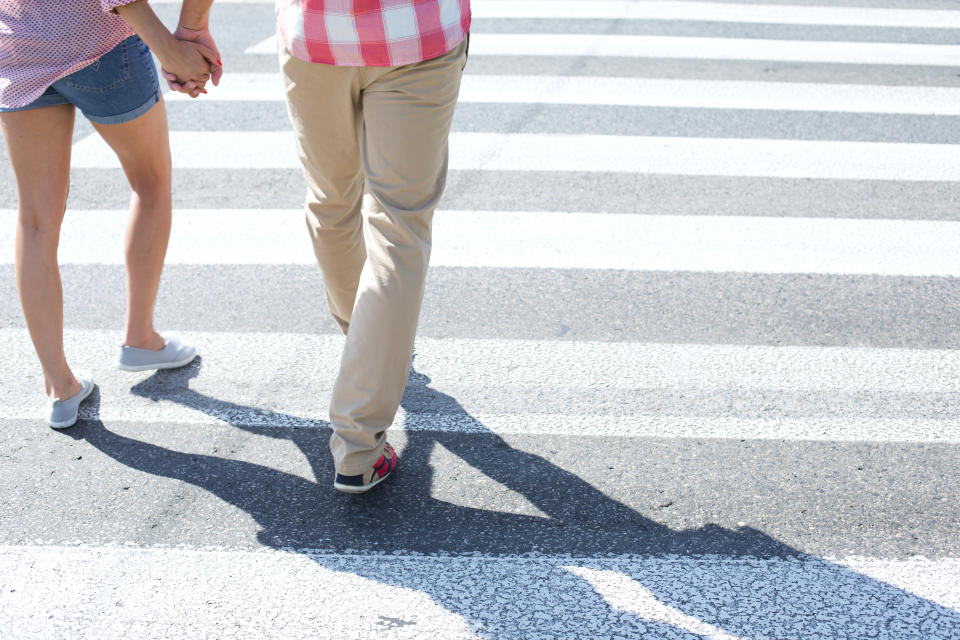 An unidentified couple walking on crosswalk while holding hands.