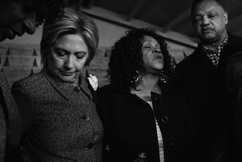 Hillary Clinton prays, accompanied by Reverend Jesse Jackson, Diane Latiker and mothers who have lost children to gun violence