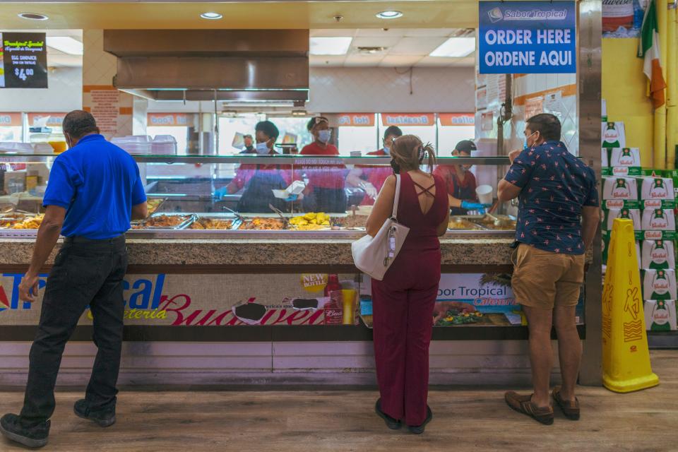 Elsa Romero waits in line to buy lunch at a supermarket March 16 in Miami.